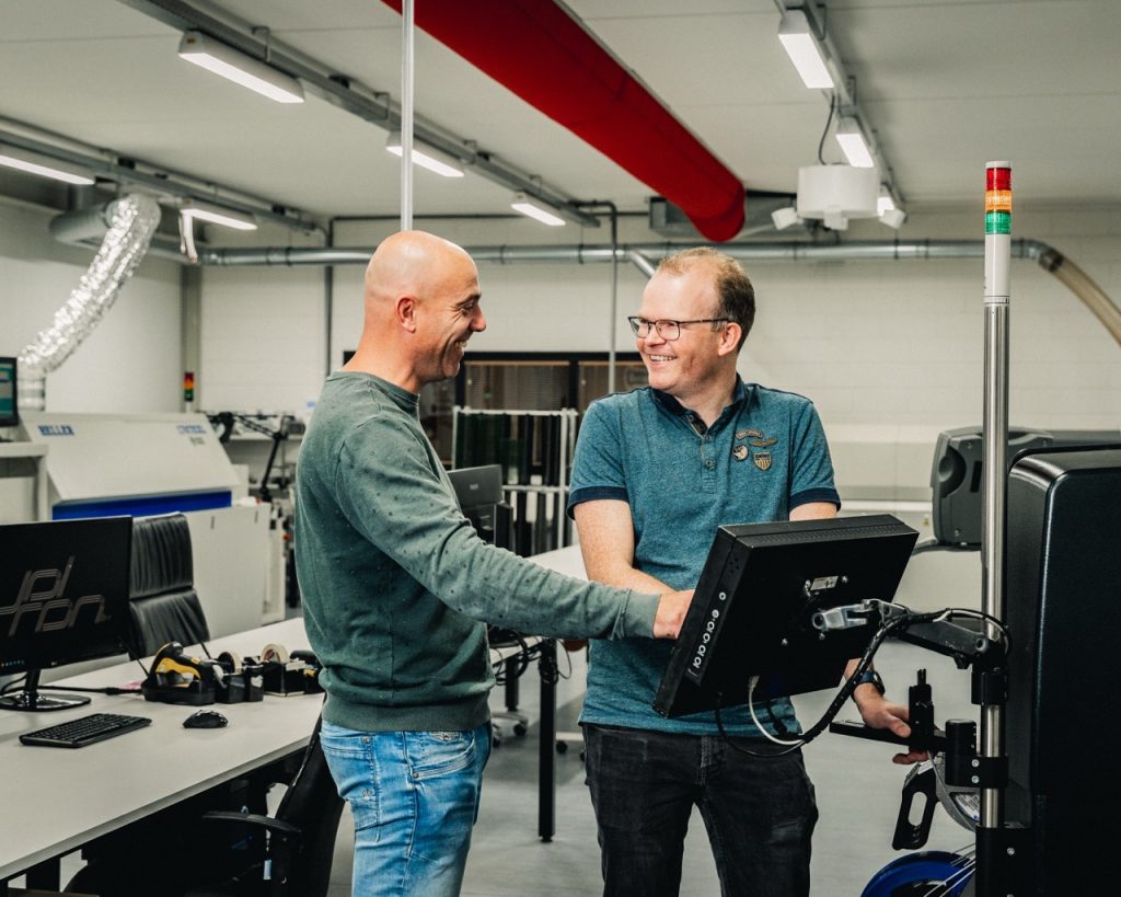 Lachende collega's Jolron, bezig achter een machine