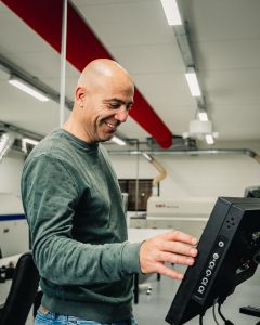 Lachende medewerker Jolron bij een machine